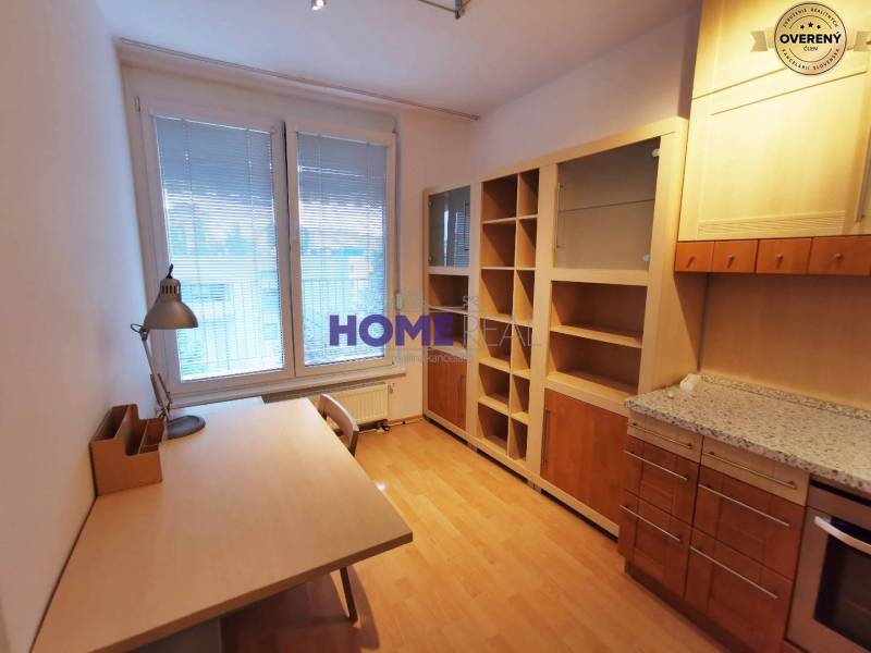 Pracovna v 2-pokojovém bytě s podlahou s dřevěným dekorem, stolem a knihovnou.