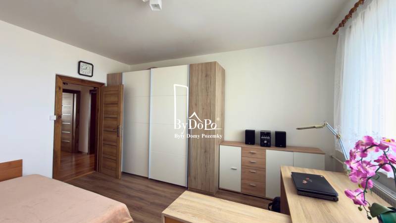 Ložnice s podlahou s dřevěným dekorem, vestavěná skříň a květina v 3-pokojovém bytě.