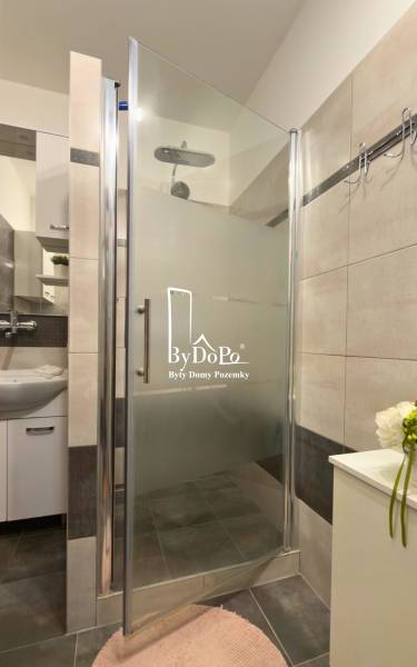 Sprchový kout s moderními obklady a umyvadlem v 3-pokojovém bytě.