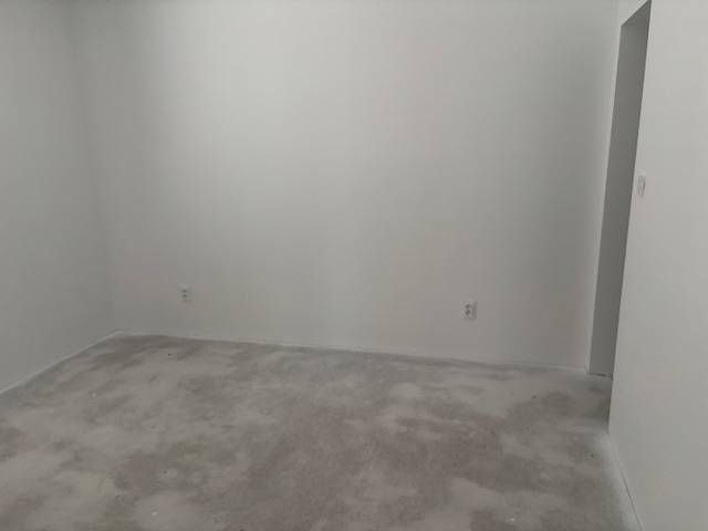 Pokoj s bílými stěnami a nevýrazným kobercem v rodinném domě.