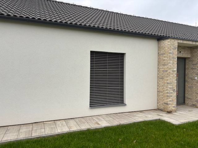 Exteriér rodinného domu na Fialkové v Tomášově s cihlovým obkladem a trávníkem.