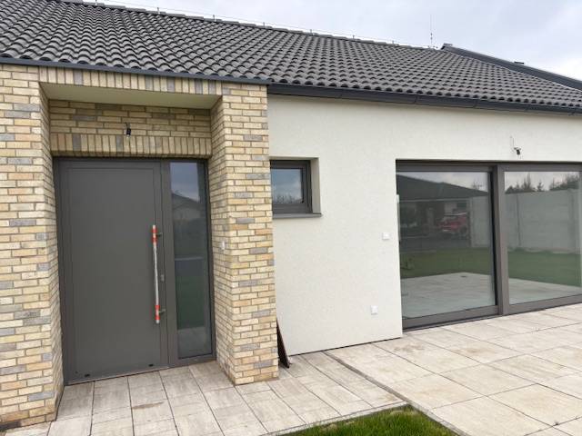 Rodinný dům na Fialkové v Tomášově s cihlovým obkladem a prostornými skleněnými dveřmi.