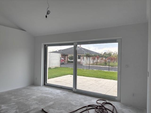 Rodinný dům se skleněnou stěnou a výhledem na zahradu.