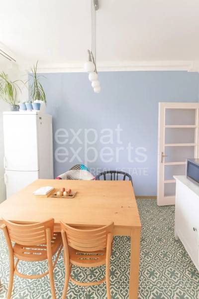 Jídelní kout v 3-pokojovém bytě s dřevěným stolem a designovou podlahou.