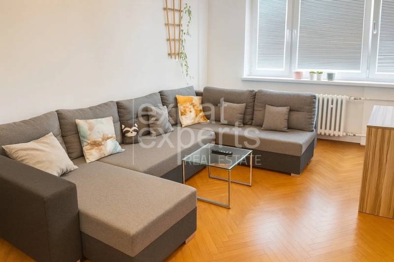 Obývací pokoj s pohodlnou sedačkou a podlahou s dřevěným dekorem v 3-pokojovém bytě.