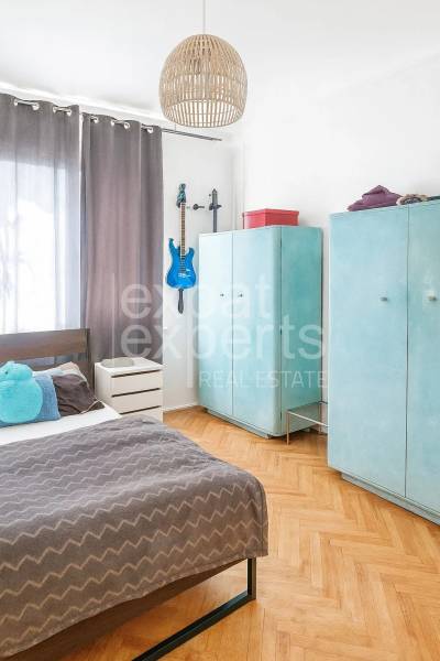 Interiér 3-pokojového bytu, dřevěný dekor podlahy, modrá kytara, útulná ložnice.