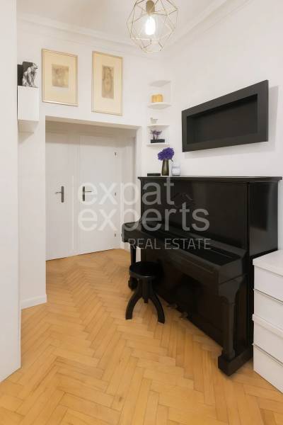 Interiér 3-pokojového bytu se starožitným černým klavírem a podlahou s dřevěným dekorem.