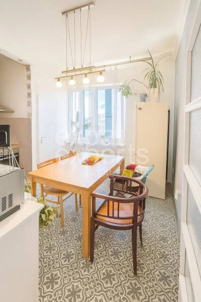 Jídelna ve 3-pokojovém bytě s dřevěným stolem, židlemi a dekorativní podlahou.