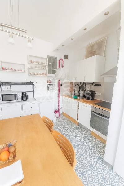 Kuchyně ve 3-pokojovém bytě s jídelním stolem, vzorovanou podlahou a bílými skříňkami.