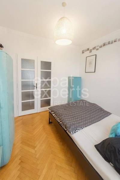 Ložnice v 3-pokojovém bytě s podlahou s dřevěným dekorem a světlými dveřmi.