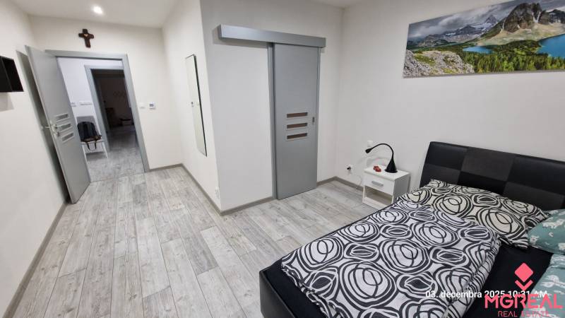 Ložnice v rodinném domě s podlahou s dřevěným dekorem a posuvnými dveřmi.