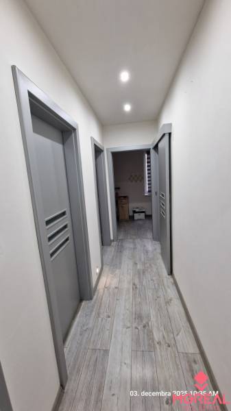 Chodba v rodinném domě s podlahou s dřevěným dekorem a šedými dveřmi.