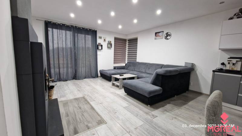 Obývací pokoj v rodinném domě s pohovkou, stolkem a podlahou s dřevěným dekorem.