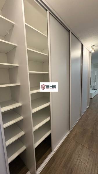 Vestavěná skříň v 1-pokojovém bytě s posuvnými dveřmi a podlahou s dřevěným dekorem.