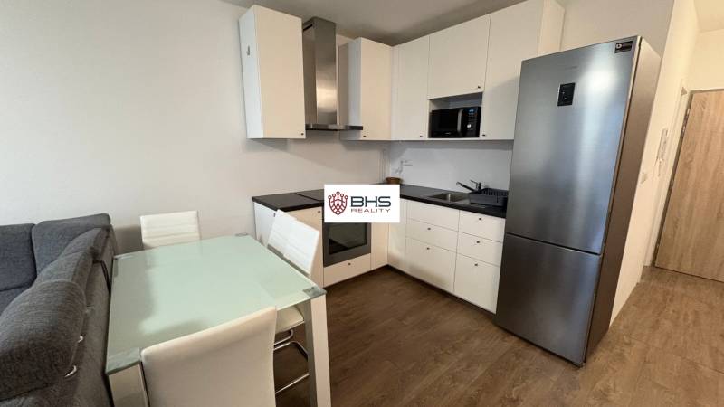 Kuchyňská linka v 1-pokojovém bytě s podlahou s dřevěným dekorem a jídelním stolem.