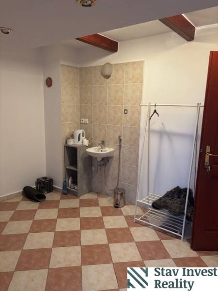 Interiér kanceláře s umyvadlem, věšákem a podlahou s dlažbou.