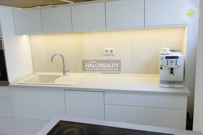 Kuchyně s bílými skříňkami a kávovarem ve 3-pokojovém bytě.