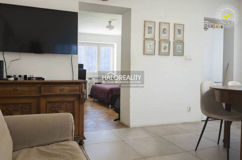 Obývací pokoj s televizí, židlemi a výhledem do ložnice ve 3-pokojovém bytě.