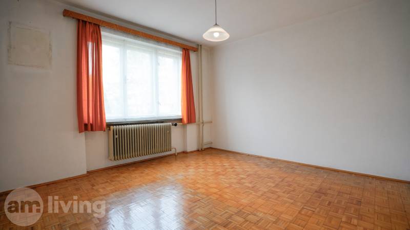 Pokoj s podlahou s dřevěným dekorem, bílými stěnami a oranžovými závěsy v rodinném domě.