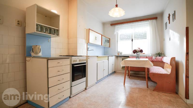 Kuchyně v rodinném domě s klasickým vybavením, rohovým sezením a oknem.