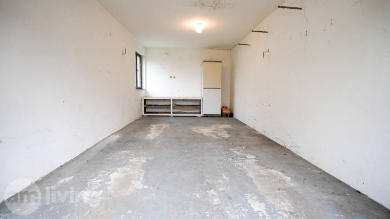 Garáž v rodinném domě s betonovou podlahou a bílými stěnami.