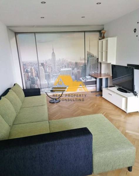 Obývací pokoj s piškotovou pohovkou, tapetou New Yorku a podlahou s dřevěným dekorem ve 3pokojovém bytě.