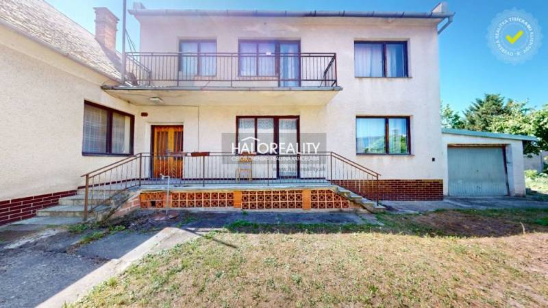 Rodinný dům v Malackách s balkónem a garáží, obklopený zahradou.