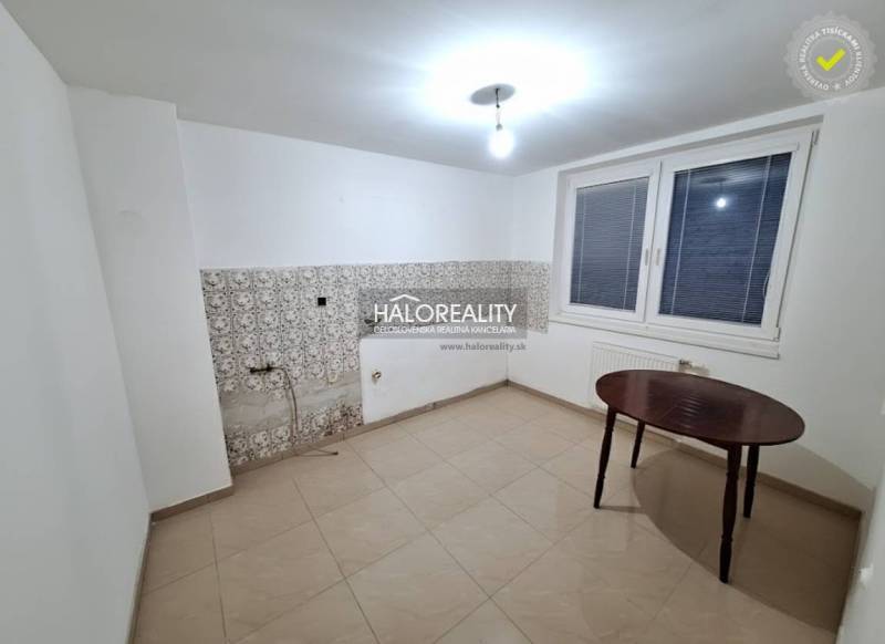 Pokoj v rodinném domě s bílými stěnami, oknem a dlaždicemi.