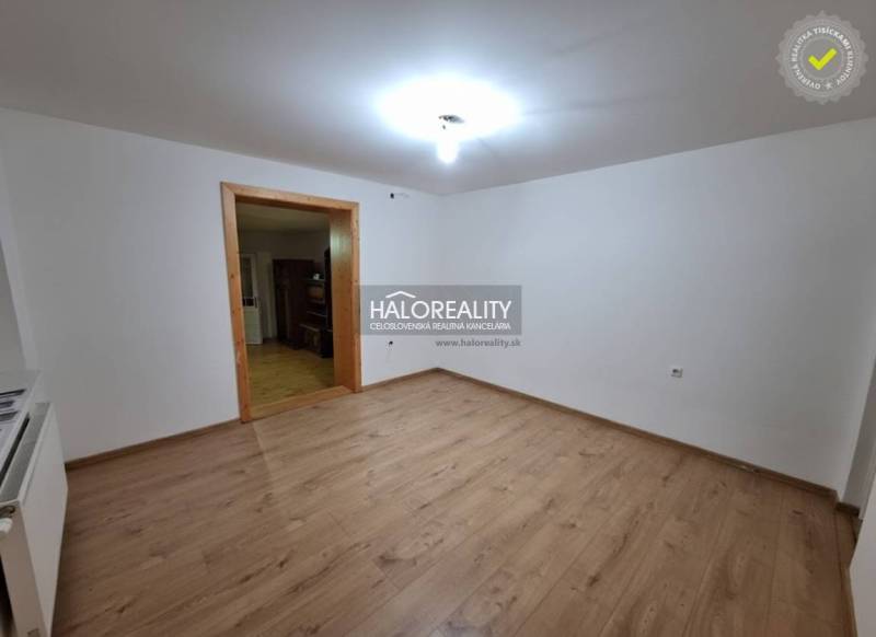 Interiér rodinného domu s podlahou s dřevěným dekorem a bílými stěnami.