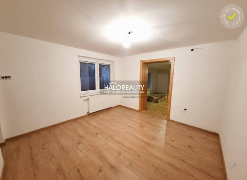 Pokoj v rodinném domě s podlahou s dřevěným dekorem a bílými stěnami.