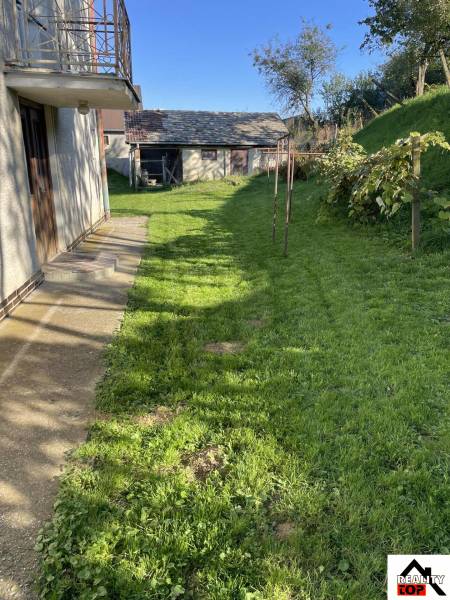 Rodinný dům v Hajnáčce s trávníkem a zahradním domkem na dvoře.