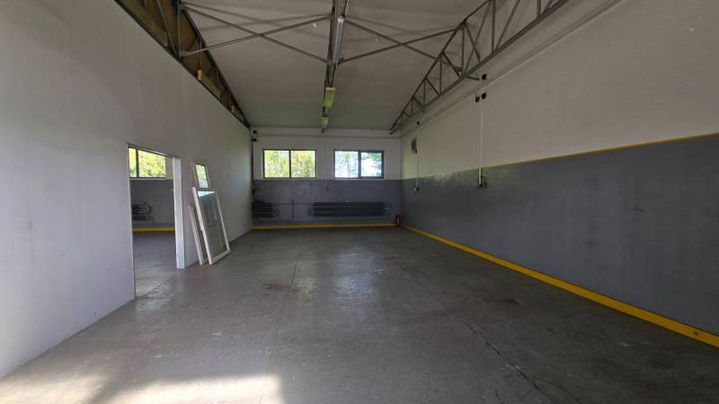 Interiér skladu s kovovou konstrukcí, betonovou podlahou a okny.