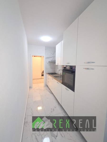 Úzká bílá kuchyně s varnou deskou a troubou, podlaha s mramorovým dekorem v 3-pokojovém bytě.