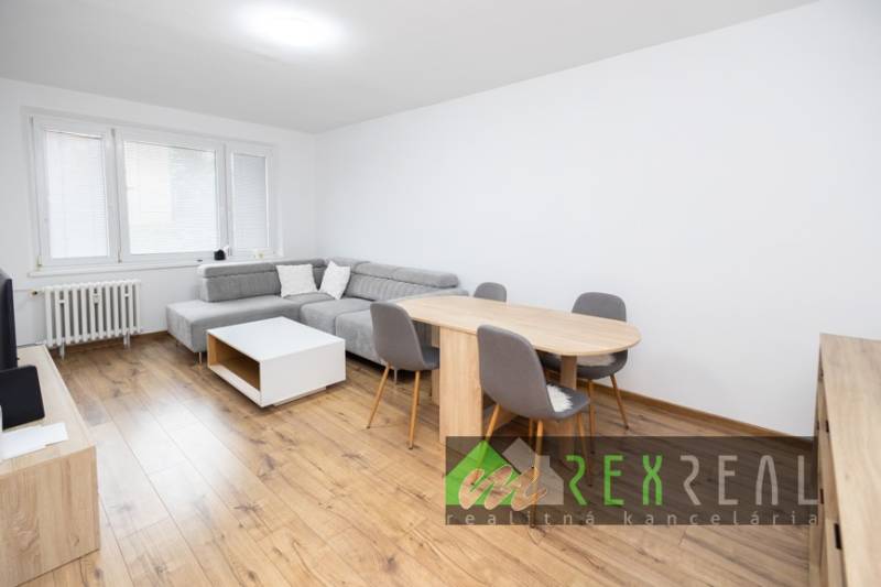 Obývací pokoj s rohovou sedačkou, jídelním stolem a podlahou s dřevěným dekorem.