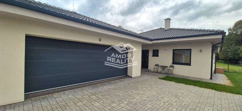 Rodinný dům ve Studience se dvěma židlemi a stolkem na dlážděném dvoře.