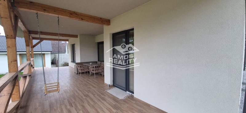 Terasa rodinného domu ve Studienke s houpací houpačkou a nábytkem, podlaha s dřevěným dekorem.