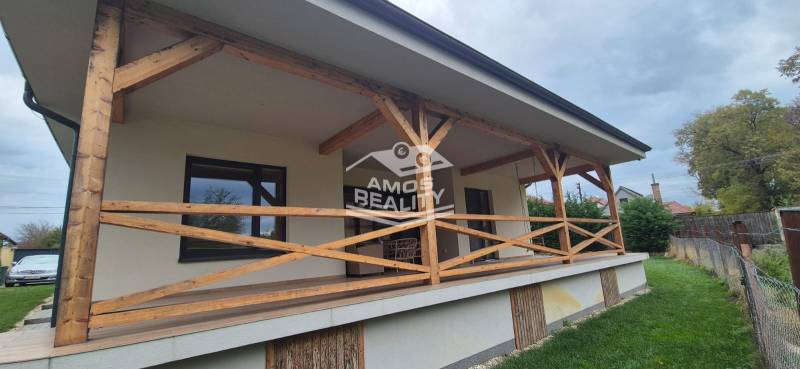 Rodinný dům ve Studience má terasu s dřevěným zábradlím a přilehlým trávníkem.