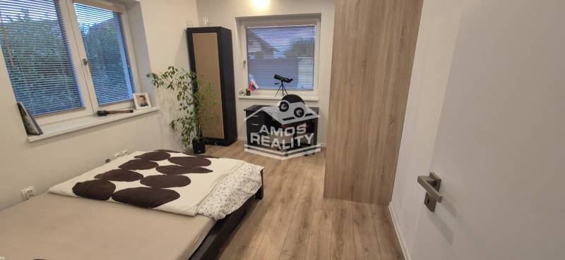 Ložnice s postelí, stolkem a podlahou s dřevěným dekorem v rodinném domě.