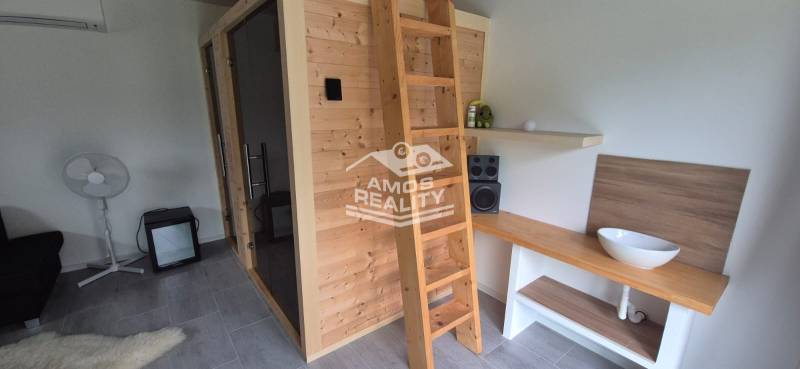 Interiér rodinného domu s dřevěnou saunou, žebříkem a stereo zařízením.