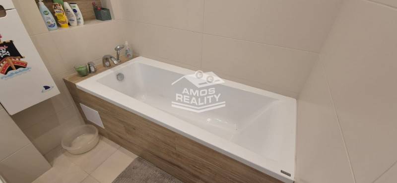 Koupelna s vanou obloženou dřevěným dekorem v rodinném domě.