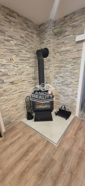 Krb na dřevo v rohu místnosti s kamenným obkladem a podlahou s dřevěným dekorem.