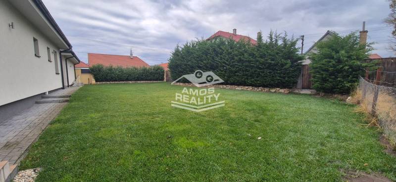 Rodinný dům ve Studience se zahradou, upraveným trávníkem a vysokým živým plotem.