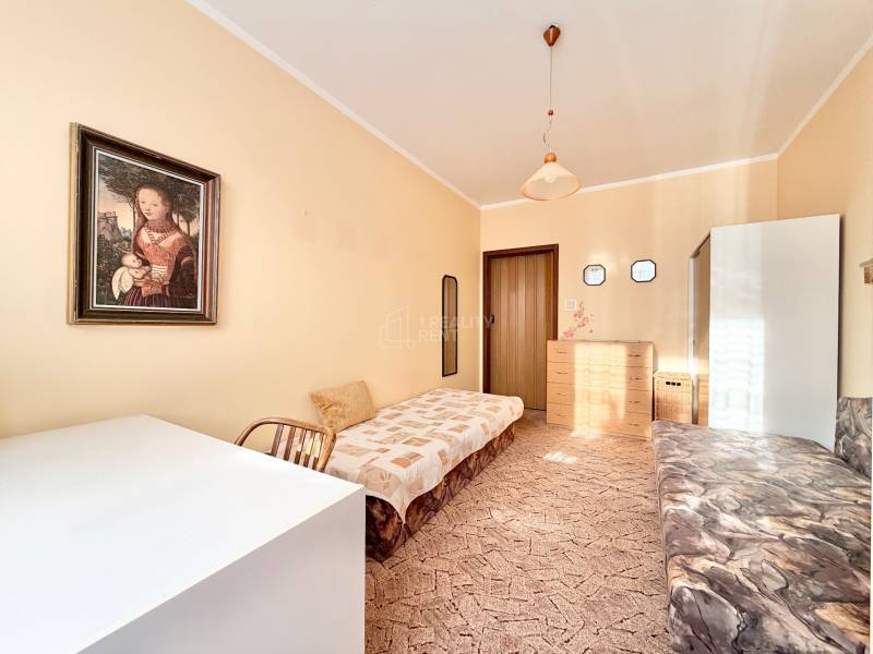 Izba s obrazom, posteľou, dreveným nábytkom a kobercom v 2-izbovom byte.