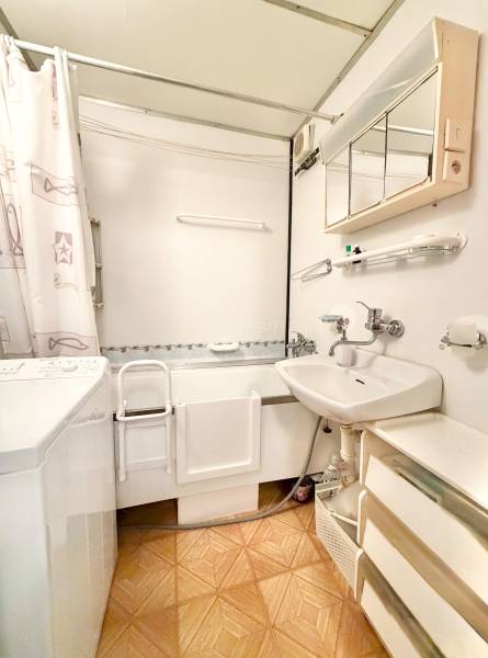 Kúpeľňa v 2-izbovom byte s vaňou, umývadlom a práčkou, podlaha s dreveným dekorom.