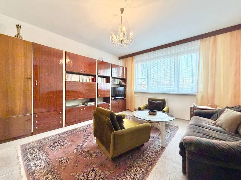 Obývacia izba v 2-izbovom byte s retro nábytkom a kobercom.