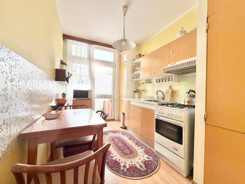 Kuchyňa v 2-izbovom byte s nábytkom a podlahou s dreveným dekorom.