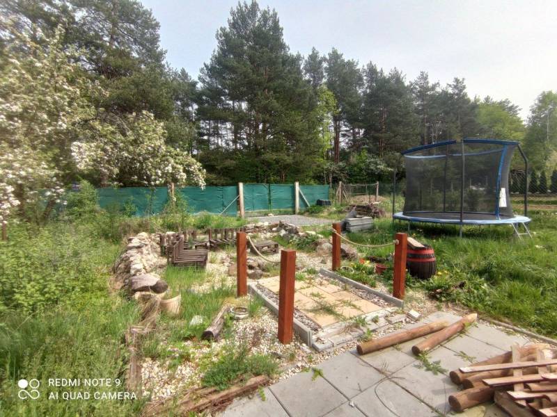 Zahrada u chaty v Hliníku nad Hronom s trampolínou a dřevěným chodníkem.