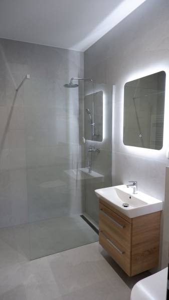 Koupelna s umyvadlem, sprchovým koutem a velkým zrcadlem v rodinném domě.