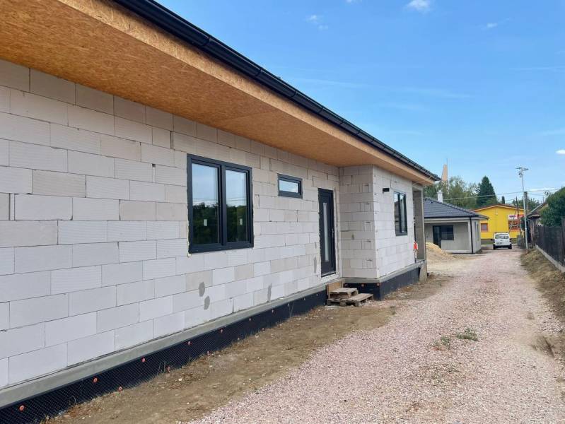 Rodinný dům v Radavě během výstavby s nezateplenou fasádou a štěrkovou cestou.