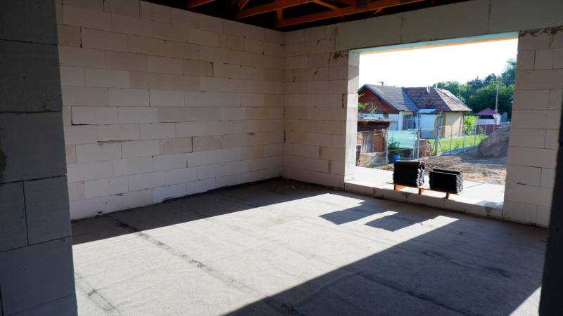 Stavba rodinného domu v Radavě s pohledem na neomítnuté stěny a okolní krajinu.